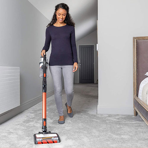  Woman using a stick vacuum cleaner