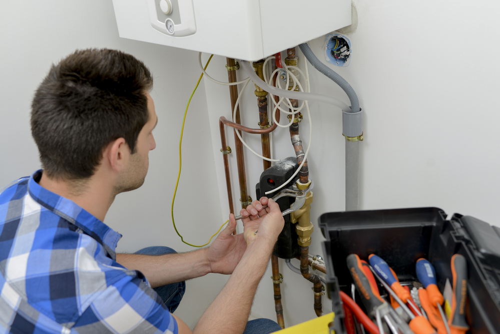 A technician fixing domestic boiler to prevent water leakage