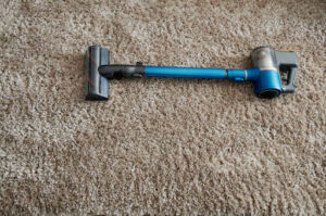 Cordless vacuum cleaner with batteries on soft carpet background